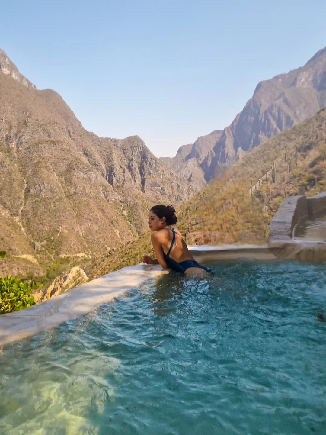 Woman seen from behind relaxing in a thermal infinity pool