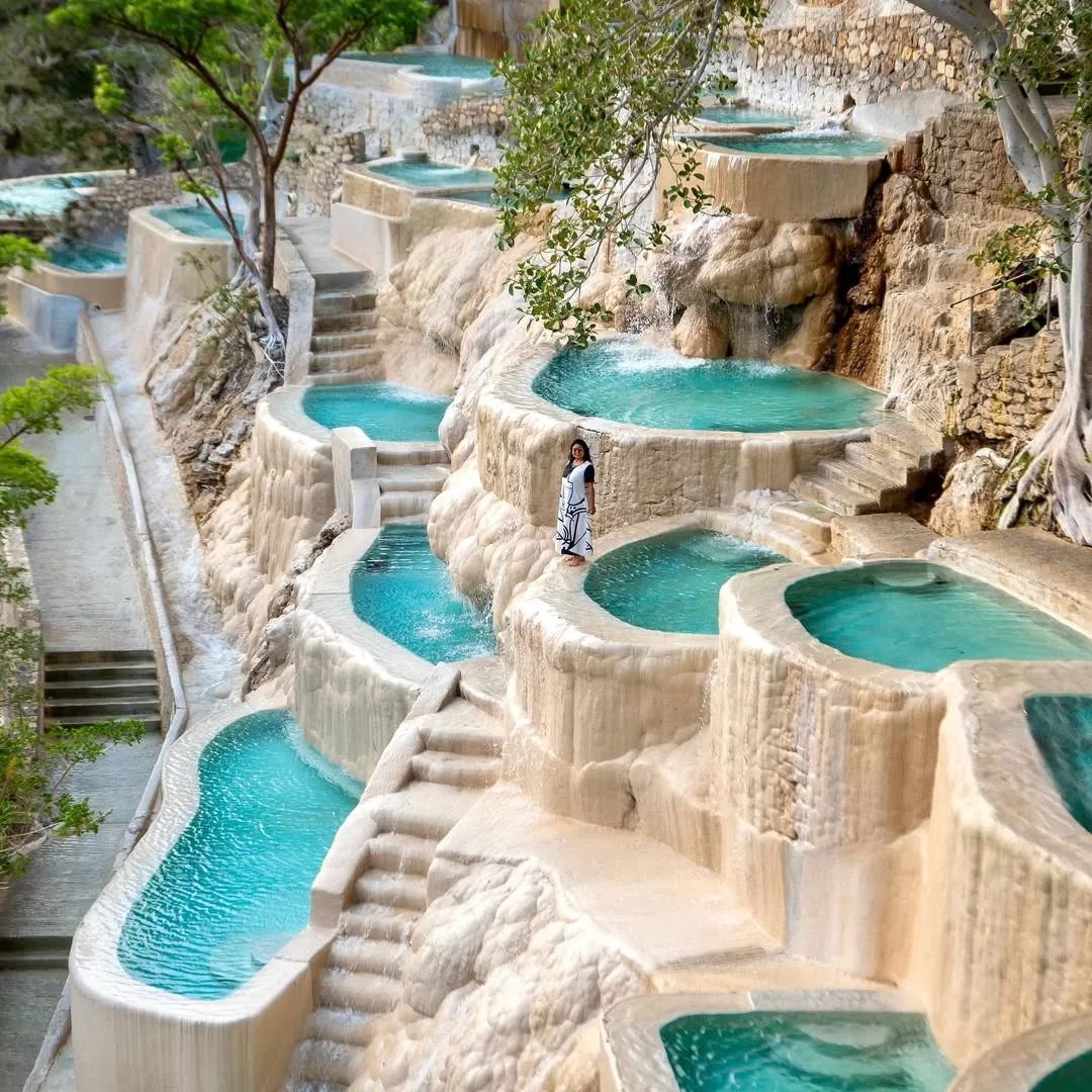 Woman in white swimsuit bathing in a thermal pool