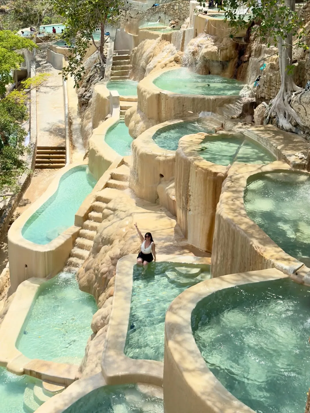 Woman raising her arm in a thermal pool celebrating the experience