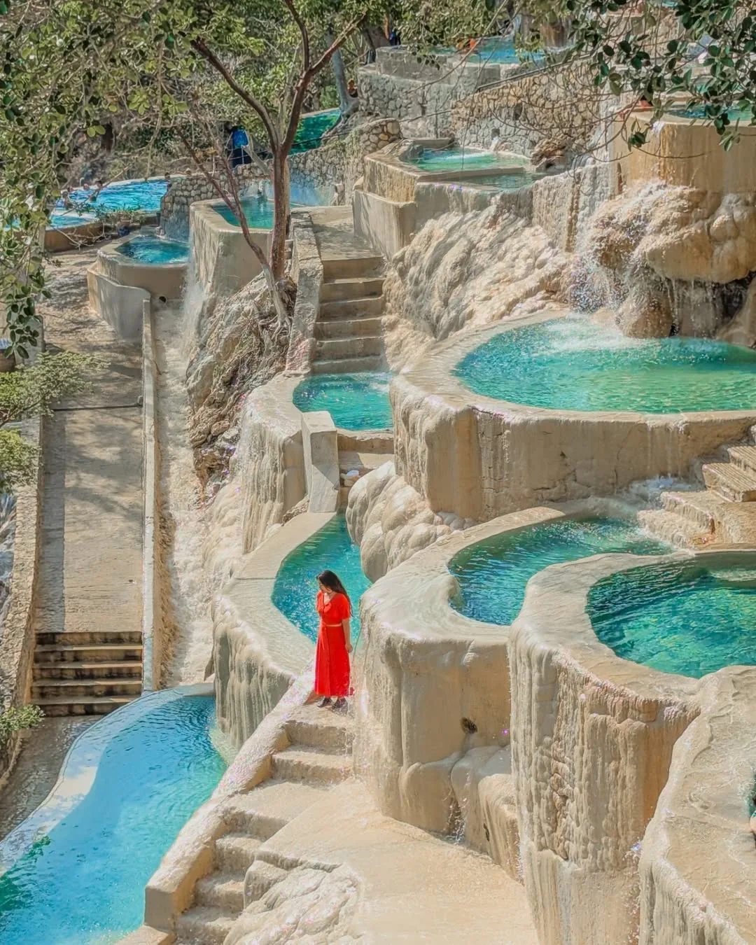 Woman in red dress posing by the thermal tiered pools